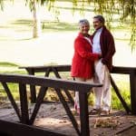 Mature couple embracing while standing on footbridge at park